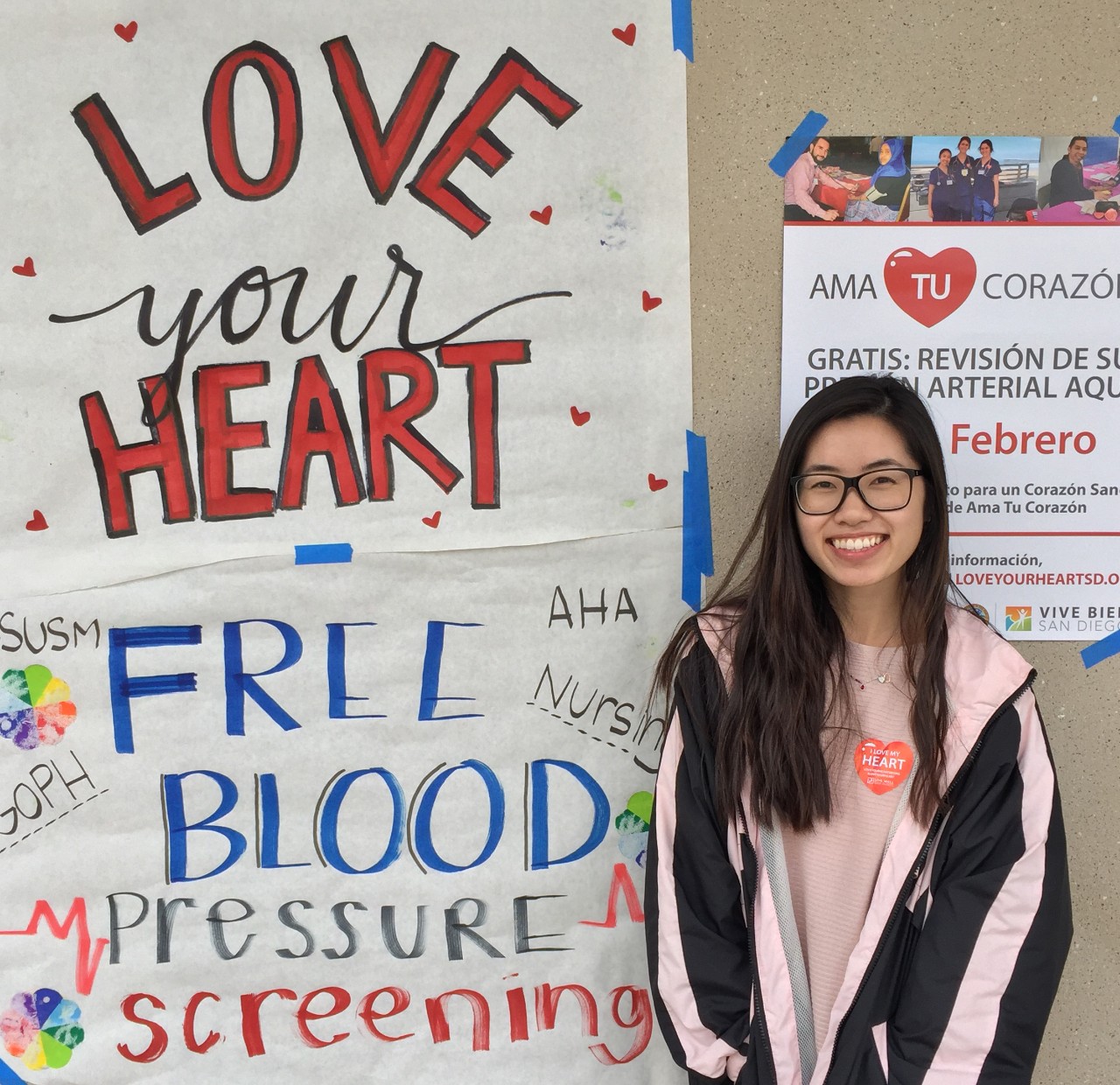 Student next to sign Love Your Heart Promotion poster