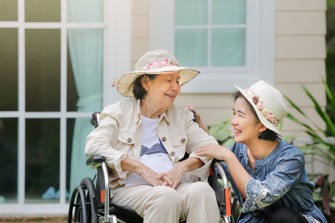Adult next to senior in wheelchair
