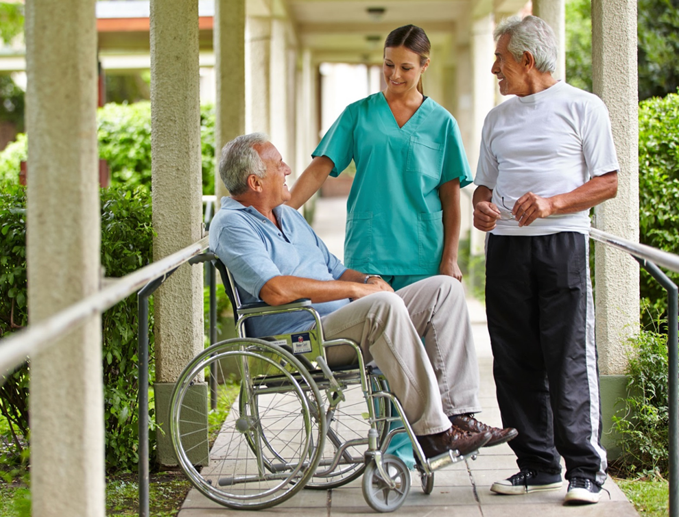Nurse standing with two seniors, one in wheelchair