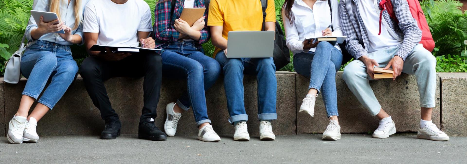 College students sitting outside working on laptops and notebooks