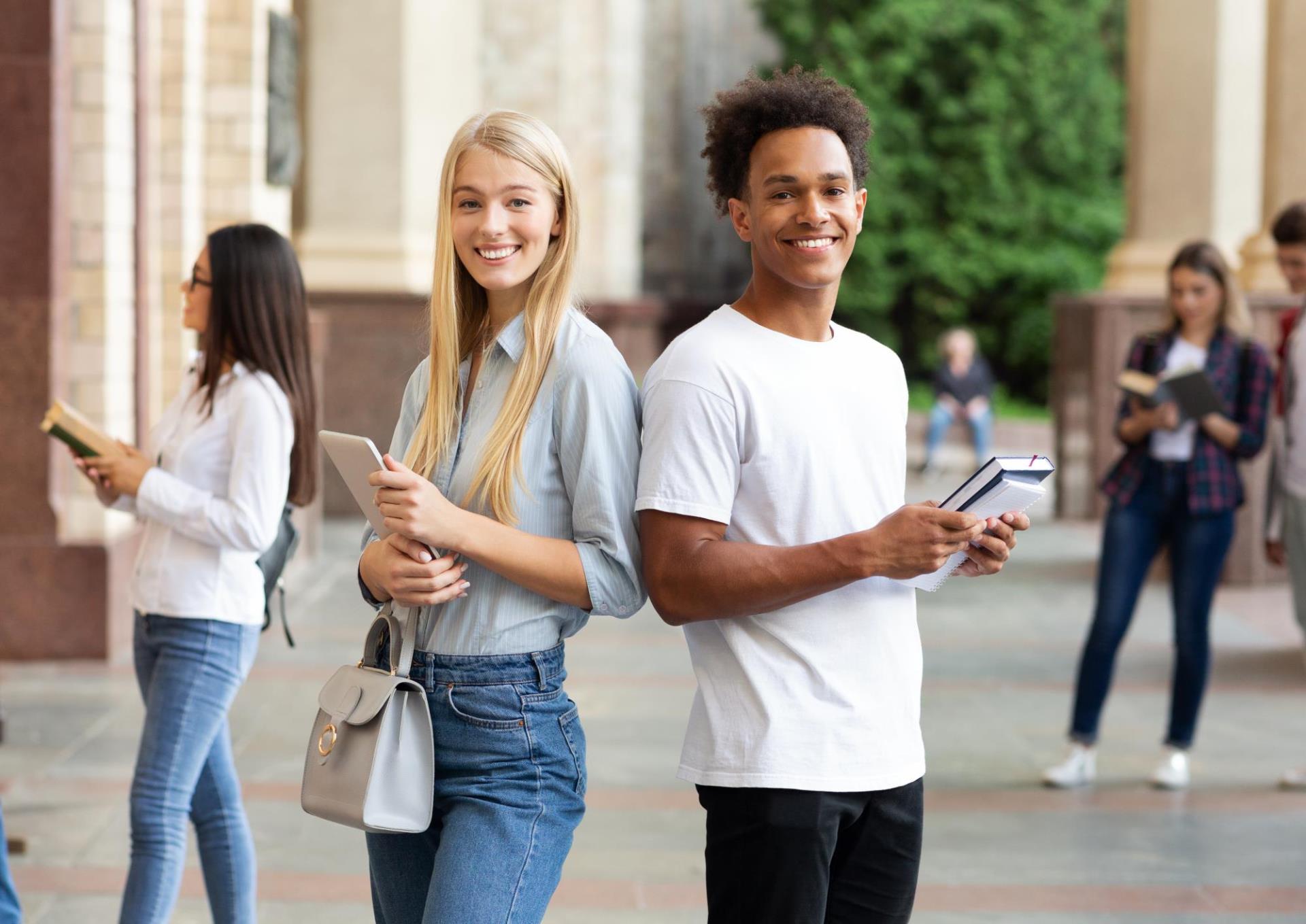 Two college students on campus with notebooks
