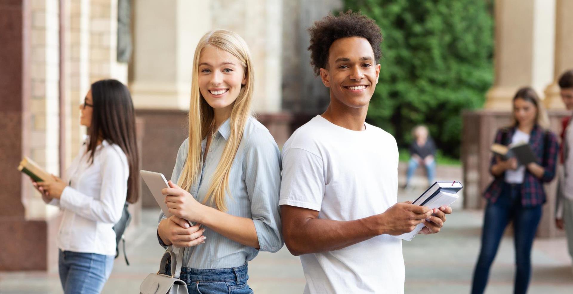 Two college students on campus with notebooks