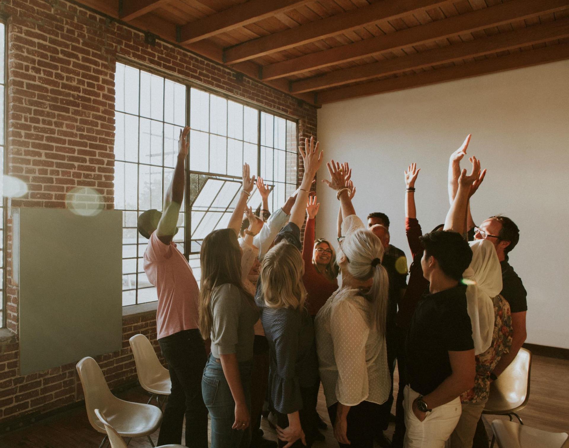 A group of happy people gathered in a circle with their hands in the air