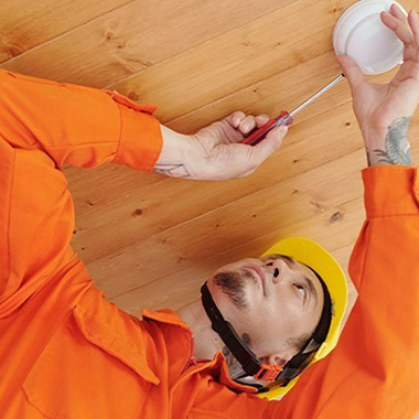 man in construction clothes changing a smoke detector