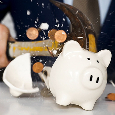 hammer breaking a full piggy bank