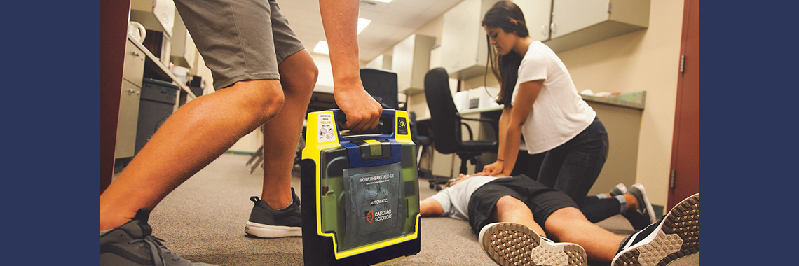 woman doing hand-only CPR as AED is brought