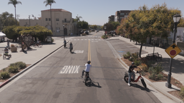 Wide shot fview of kids riding bikes in empty street with proper safety equipment