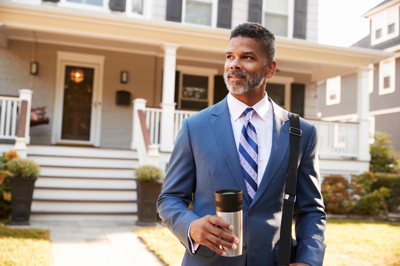 businessman standing outside house holding coffee