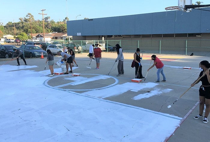 Resident Leadership Academy participants painting community basketball court