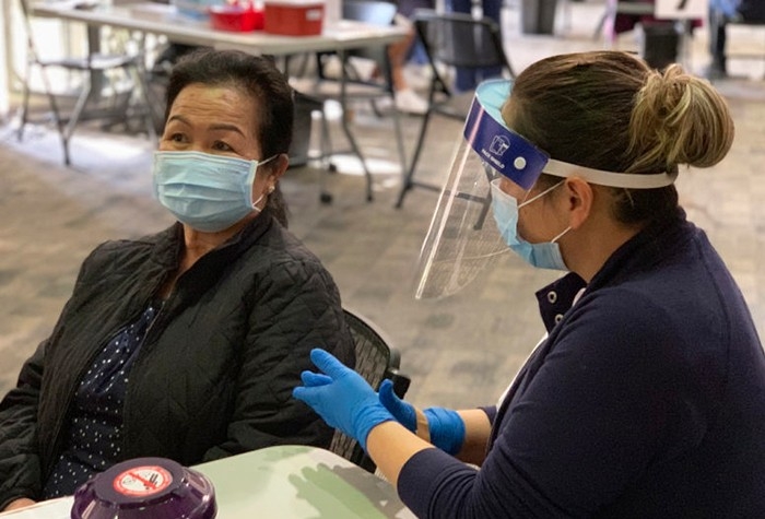 Masked healthcare worker and patient in vaccine distribution center